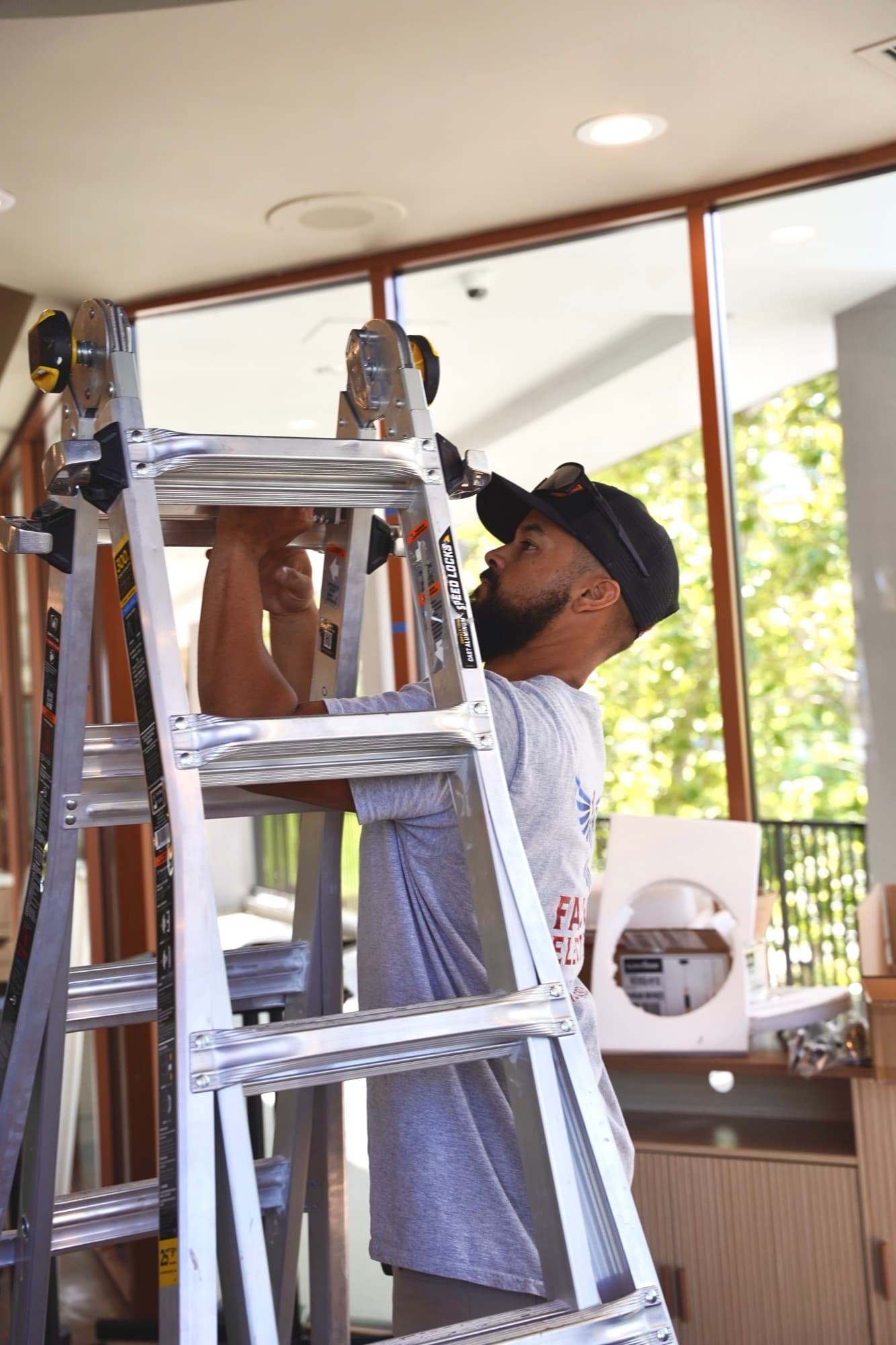 Ean Orchard on a ladder installing a recessed ceiling fixture