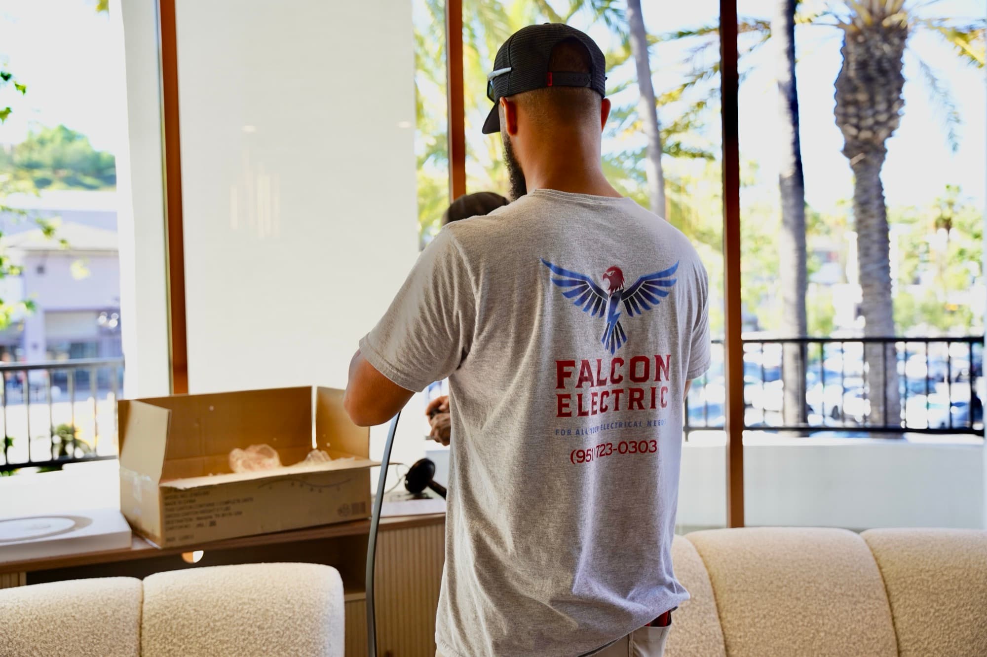 Falcon Electric branded shirt close-up — red falcon mark with phone (951) 723-0303
