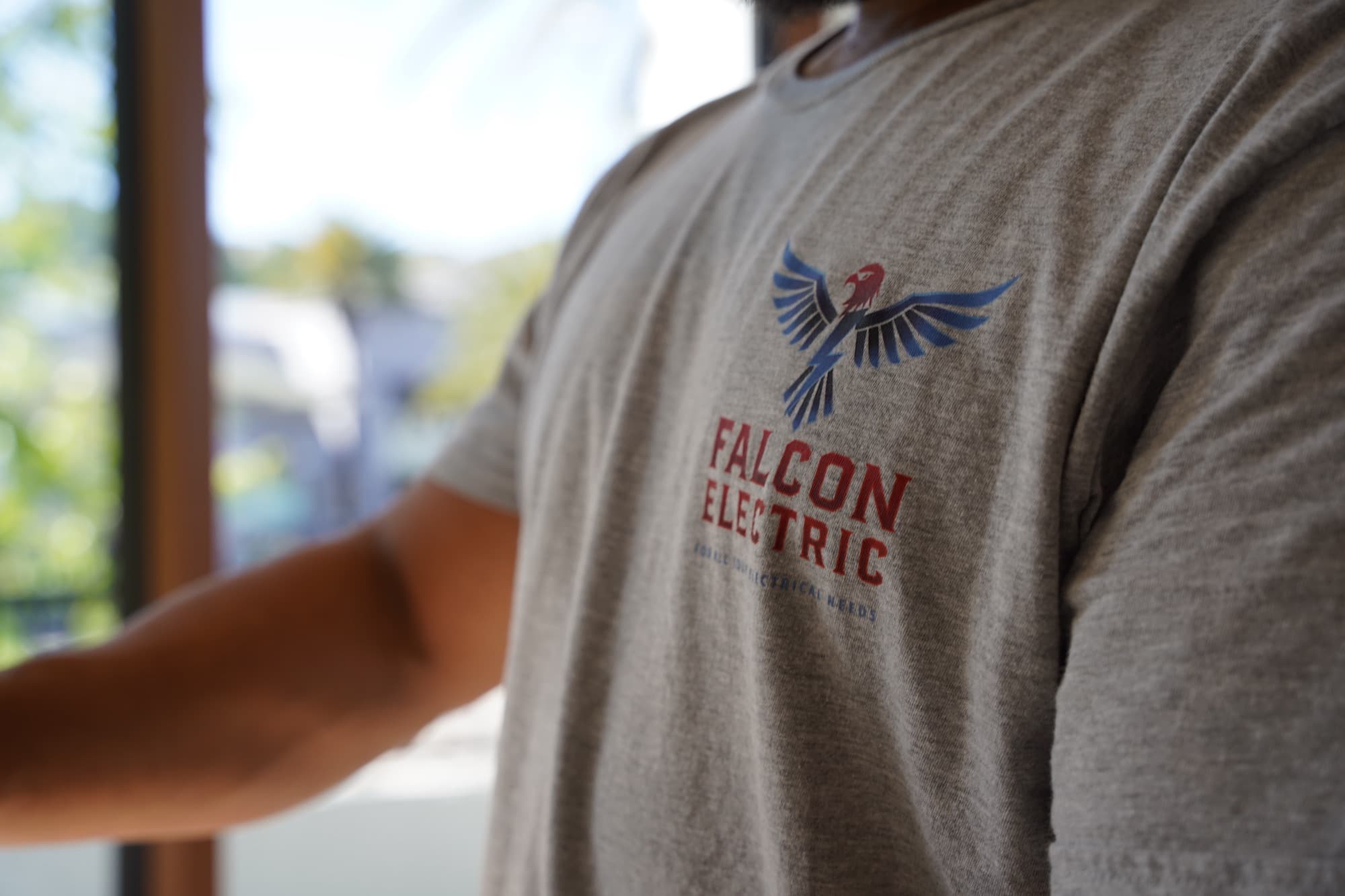 Falcon Electric shirt logo close-up — falcon mark and FOR ALL YOUR ELECTRICAL NEEDS tagline