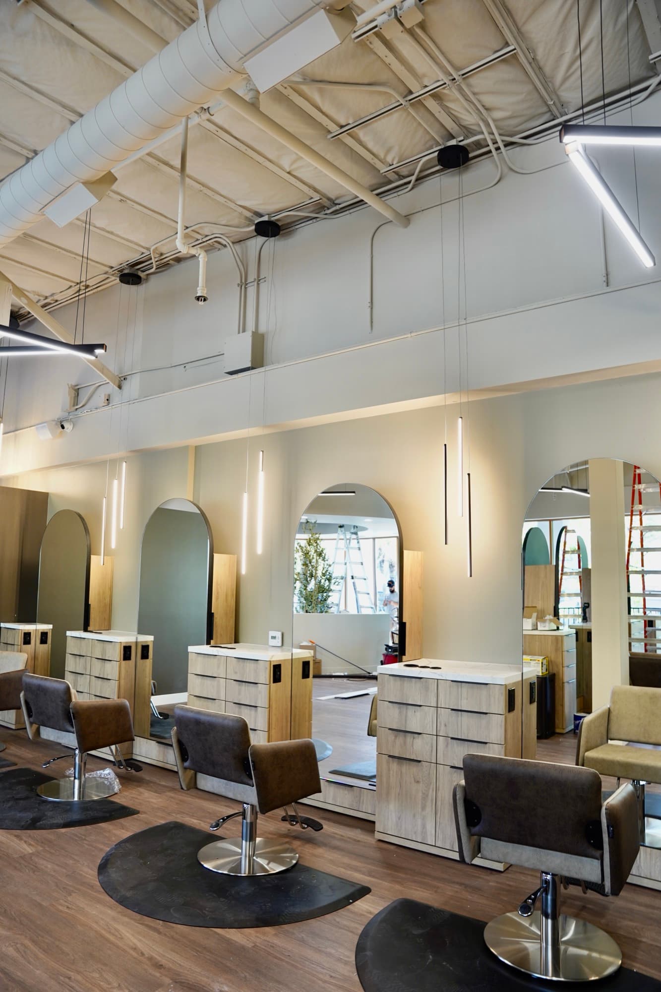 Salon styling chairs and arched mirrors lit by Falcon Electric pendants