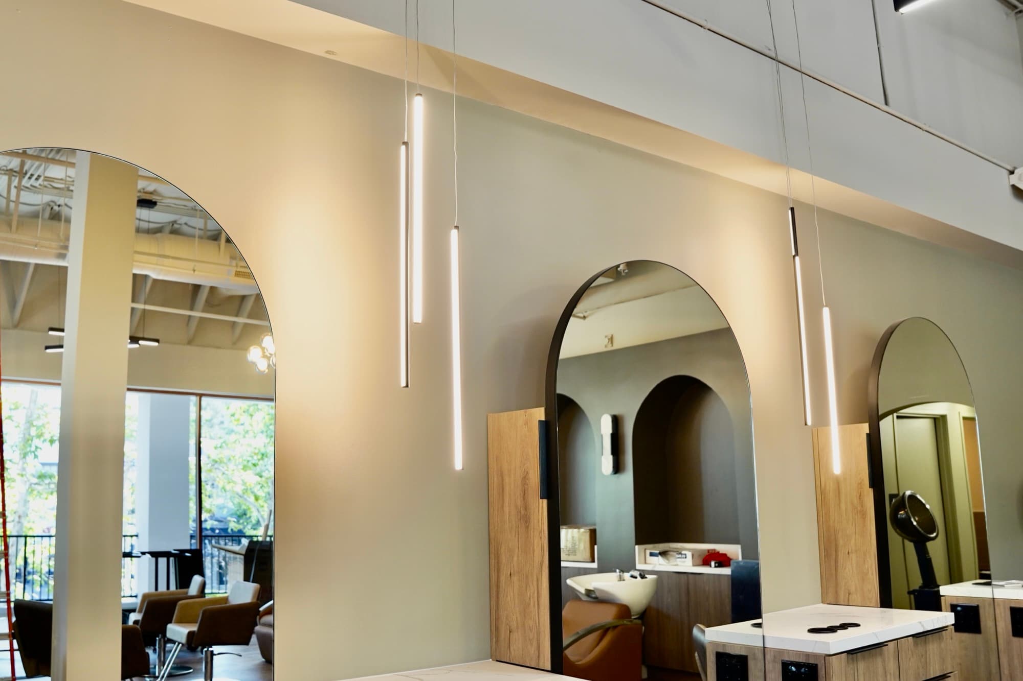 Modern salon interior with pendant lighting installed by Falcon Electric — arched mirrors and warm wood